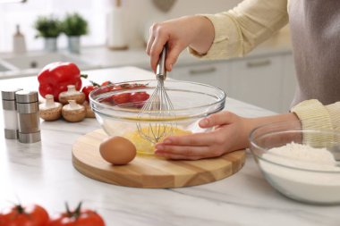 Açık mermer masada yumurta çırpan bir kadın, yakın plan.