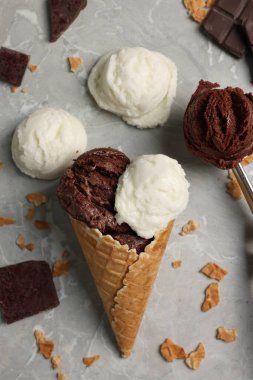 Lezzetli dondurma kepçeleri, çikolata parçaları ve açık mermer masada waffle külahı ile düz bir kompozisyon.