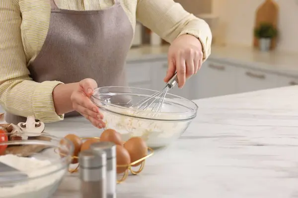 stock image Woman making dough with whisk in bowl at light marble table, closeup. Space for text