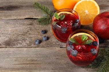 Aromatik Noel Sangria kadehleri, köknar dalları ve ahşap masadaki malzemeler. Metin için boşluk