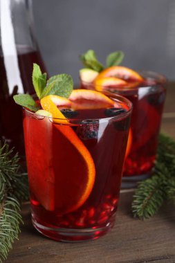 Aromatik Noel Sangria içeceği ve ahşap masada köknar dalları, yakın plan.