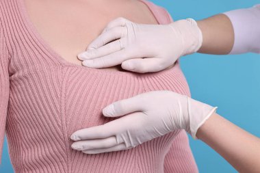 Mamolog açık mavi arka planda kadınların göğüslerini kontrol ediyor.