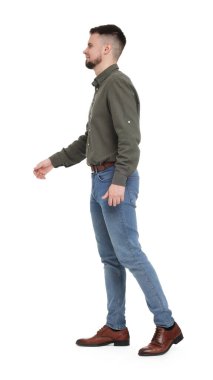 Gömlekli ve kot pantolonlu bir adam beyaz arka planda yürüyor.