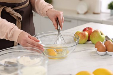 Açık mermer masada yumurta çırpan bir kadın, yakın plan.