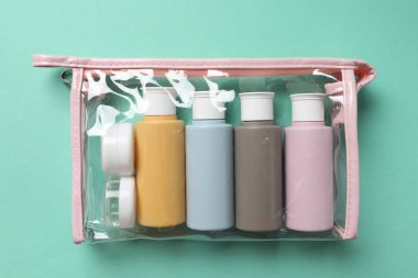 Turkuaz arka planda plastik poşette kozmetik seyahat seti, üst manzara. Banyo aksesuarları
