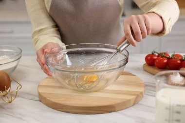 Açık mermer masada yumurta çırpan bir kadın, yakın plan.