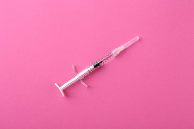 Kozmetik enjeksiyonu. Pembe arka planda bir tıbbi şırınga.
