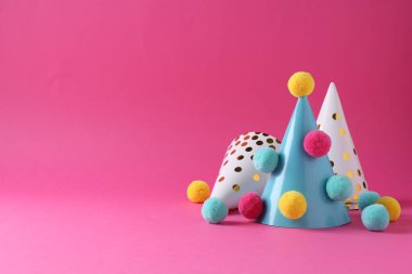 Pembe arka planda renkli ponponları olan parti şapkaları, metin için boşluk