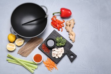 Wok, yemek çubukları ve gri masada farklı ürünler, düz yatak. Metin için boşluk