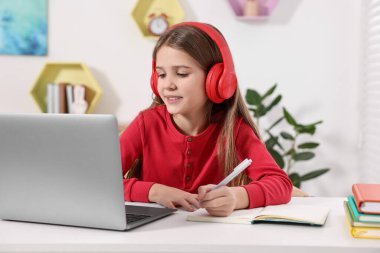 E-öğrenme. İçerideki masada online ders sırasında not alan tatlı kız.
