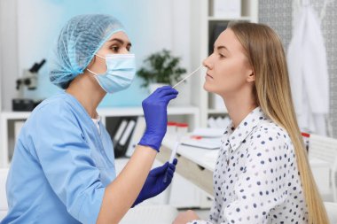 Laboratuvar testi. Doktor hastanedeki pamuklu bezle hastanın burnundan örnek alıyor.