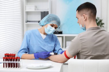 Laboratuvar testi. Doktor hastanedeki beyaz masadaki hastadan kan örneği alıyor.