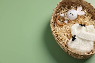 Yeşil arka planda, hasır kutuda farklı bebek aksesuarları, üst manzara. Metin için boşluk