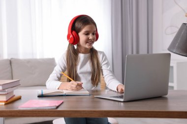 E-öğrenme. İçerideki masada online ders sırasında not alan tatlı kız.