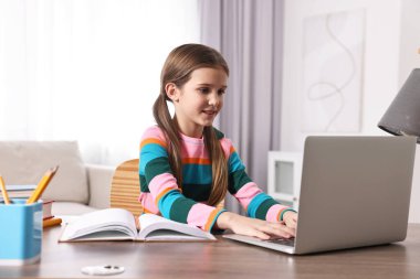 E-öğrenme. İçerideki masada online ders sırasında dizüstü bilgisayar kullanan tatlı bir kız.