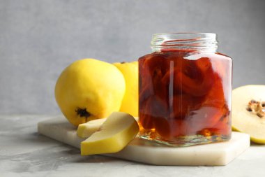 Kavanozda ev yapımı ayva reçeli ve gri desenli masada meyveler, yakın plan. Metin için boşluk