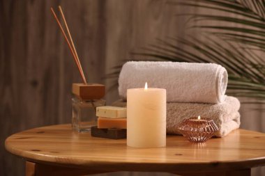 Spa kompozisyonu. Yanan mumlar, havlular, sabun ve kamış oda spreyi ahşap masada, yakın plan.