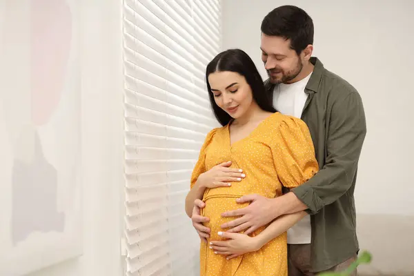 Stock image Pregnant woman with her husband indoors, space for text