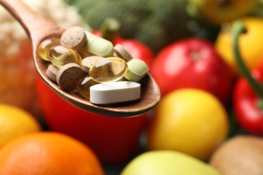 Beslenme takviyeleri. Yiyecek ürünlerinin üzerinde farklı haplar olan kaşık, yakın çekim. Metin için boşluk