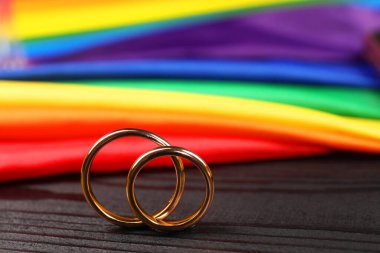 Gökkuşağı LGBT bayrağı ve siyah ahşap arka planda alyanslar, yakın plan