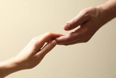 Erkek ve kadın bej arka planda el ele tutuşuyorlar, yakın plan.