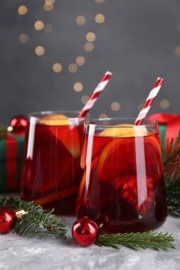 Gözlüklü lezzetli Sangria içkisi ve gri desenli masa üzerindeki Noel süslemeleri, yakın plan.