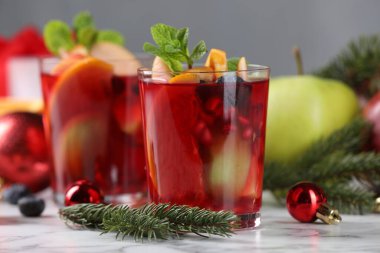 Aromatik Sangria içeceği bardaklarda, malzemelerde ve beyaz mermer masada Noel dekorunda.