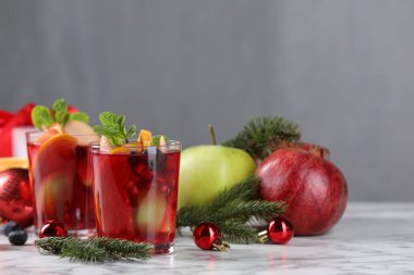 Aromatik Sangria içeceği bardaklarda, malzemelerde ve beyaz mermer masada Noel dekorunda.