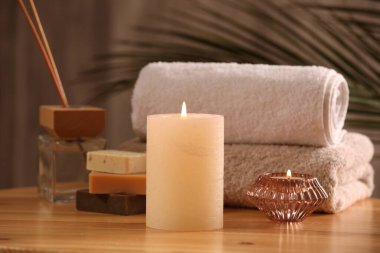 Spa kompozisyonu. Yanan mumlar, havlular, sabun ve kamış oda spreyi ahşap masada, yakın plan.