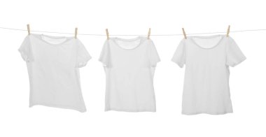 Çamaşır ipinde kuruyan birçok tişört beyaza izole edilmiş.