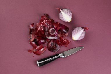 Kırmızı soğanları kabuklu ve bıçağı koyu pembe arka planda kes, düz yat.