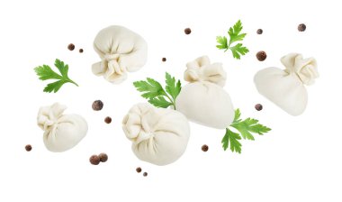 Lezzetli khinkali, biberler ve beyaz arka planda uçuşan maydanoz.