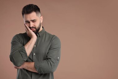 Kahverengi arkaplanda üzgün bir adamın portresi, metin için boşluk