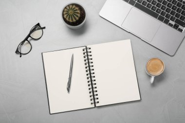 Açık defter ve dizüstü bilgisayarla açık gri masada düz kompozisyon