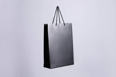 Gri arkaplanda bir siyah kağıt alışveriş çantası