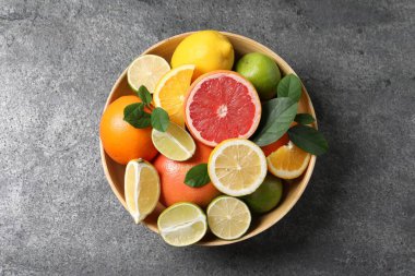 Farklı taze narenciye ve yapraklar gri desenli masada, üst tarafta.