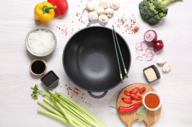 Wok, yemek çubukları ve beyaz ahşap masa üzerinde farklı ürünler, düz konum