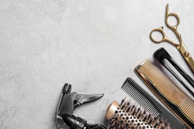 Gri dokulu arka planda profesyonel kuaför aletleri, düz yatış. Metin için boşluk