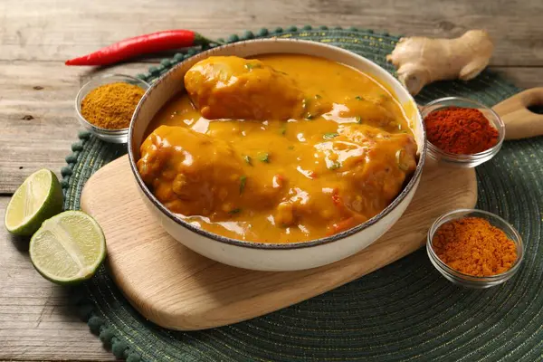 stock image Tasty chicken curry and ingredients on wooden table