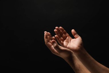 Din. Avuç içleri açık siyah arka planda dua eden adam, yakın plan. Metin için boşluk