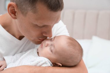 Baba tatlı uyuyan bebeğini kucağında tutuyor, yakın plan.