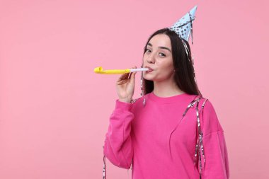 Parti şapkalı kadın, hava üfleyicili ve pembe arka planda flamalar, mesaj için yer