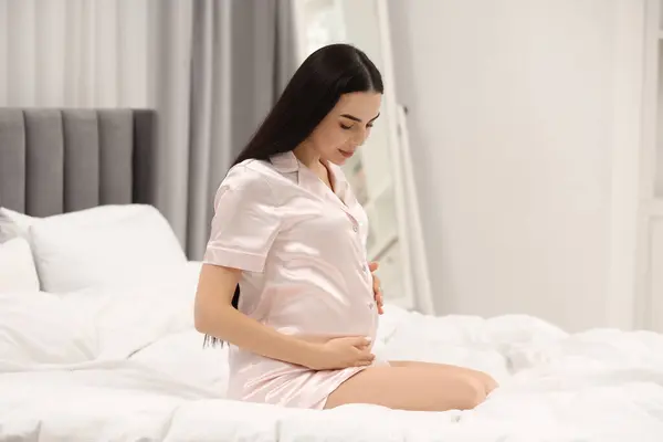 Pregnant young woman on bed at home