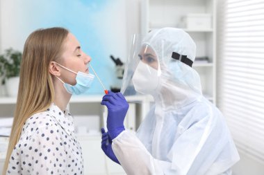 Laboratuvar testi. Üniformalı doktor hastanedeki pamuklu bezle hastanın burnundan örnek alıyor.