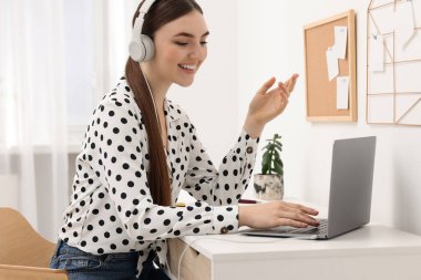 E-öğrenme. İçerideki masada online ders sırasında dizüstü bilgisayar kullanan genç bir kadın.