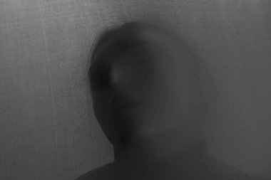 Gri kumaşın arkasındaki tüyler ürpertici hayalet silueti. Siyah ve beyaz etkisi