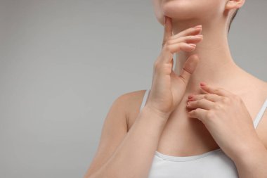 Gri arka planda çenesine dokunan kadın, yakın plan. Metin için boşluk