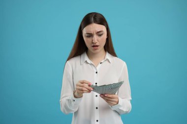 Açık mavi arka planda dolar banknotları olan kadın