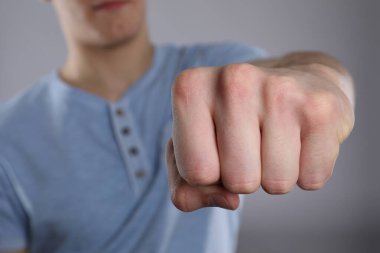 Gri arkaplanda dövmesi için yer açılmış yumruğunu gösteren adam, seçici odak