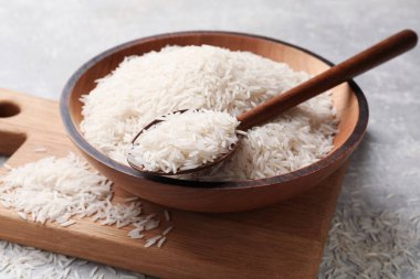 Tabakta çiğ basmati pilavı ve gri masada kaşık.